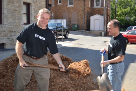 Secretary Siedlecki and Legislative Director Gary Haulmark spread new mulch over a playground at the school.